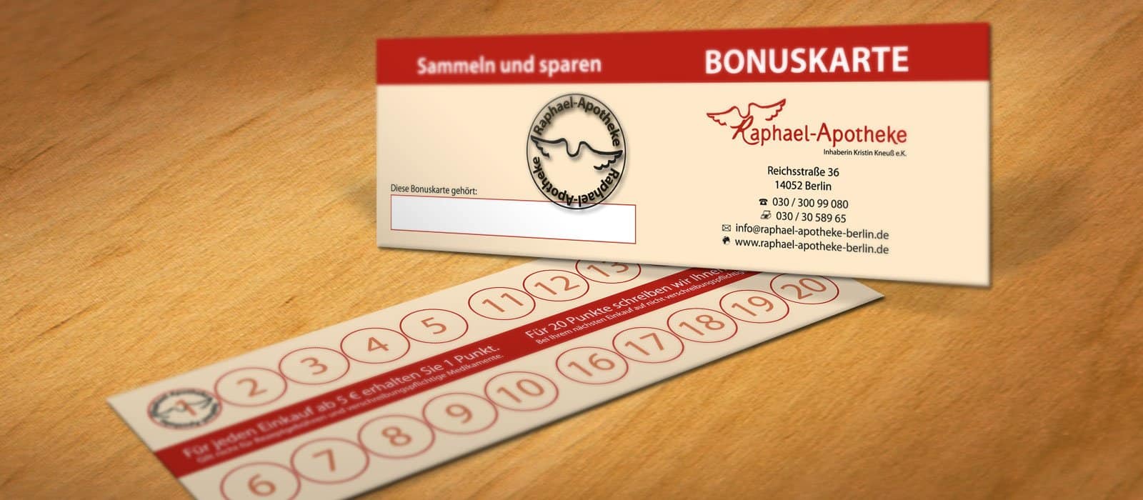 Symbolfoto zeigt die Bonuskarte der Raphael-Apotheke auf einem Holzuntergrund.