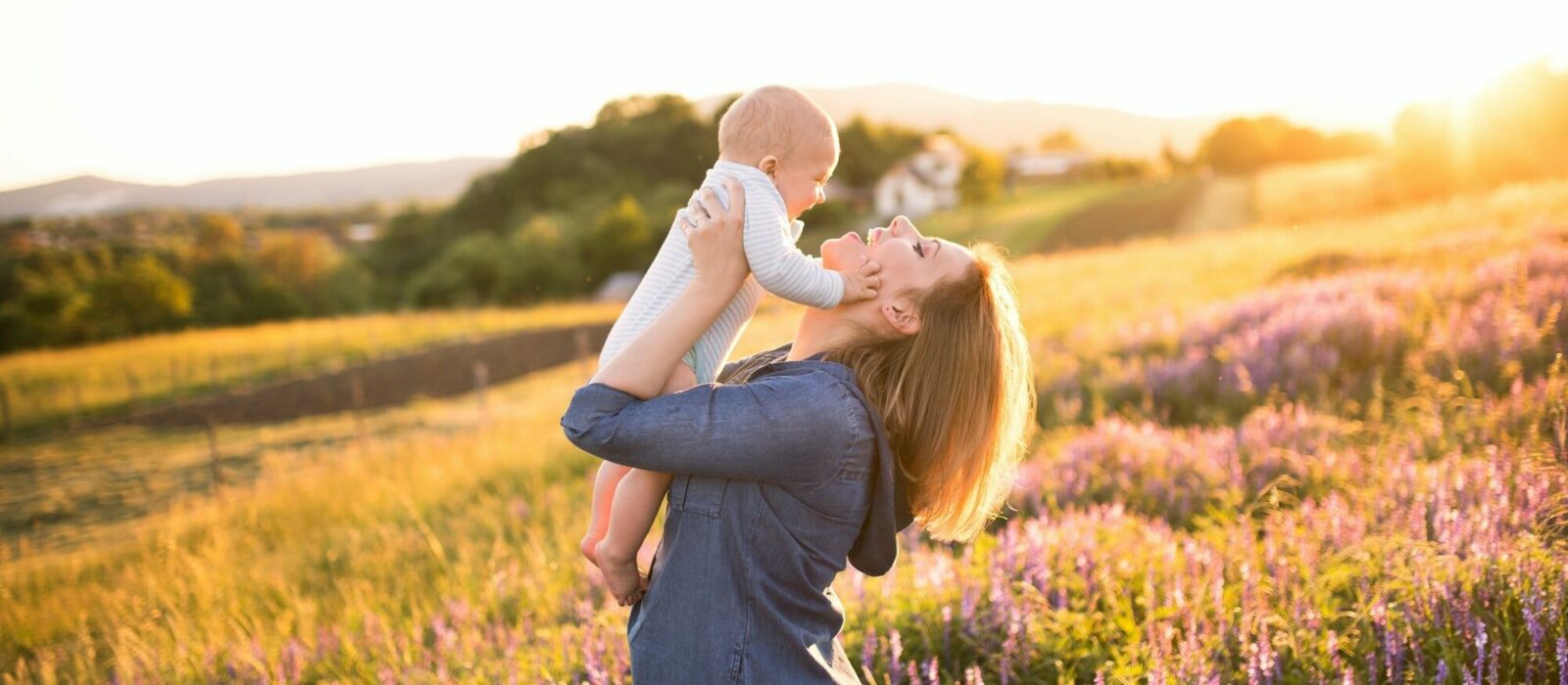 Symbolbild Weleda Naturkosmetik zeigt eine Frau auf einem Feld mit ihrem Sohn im Arm