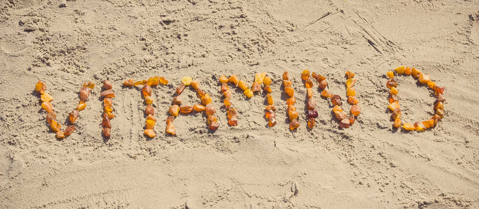 Symbolbild Vitamin D: zeigt den Text Vitamin D mit steinen im Sand